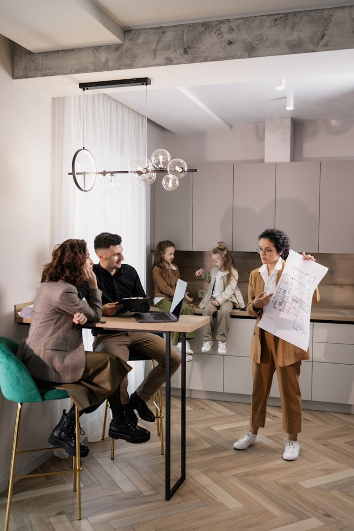Real estate agent presents house plans to a family in a modern kitchen setting, fostering discussion and planning.